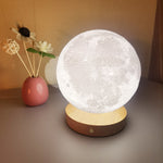 Rotating moon night lamp glowing white on a wooden base